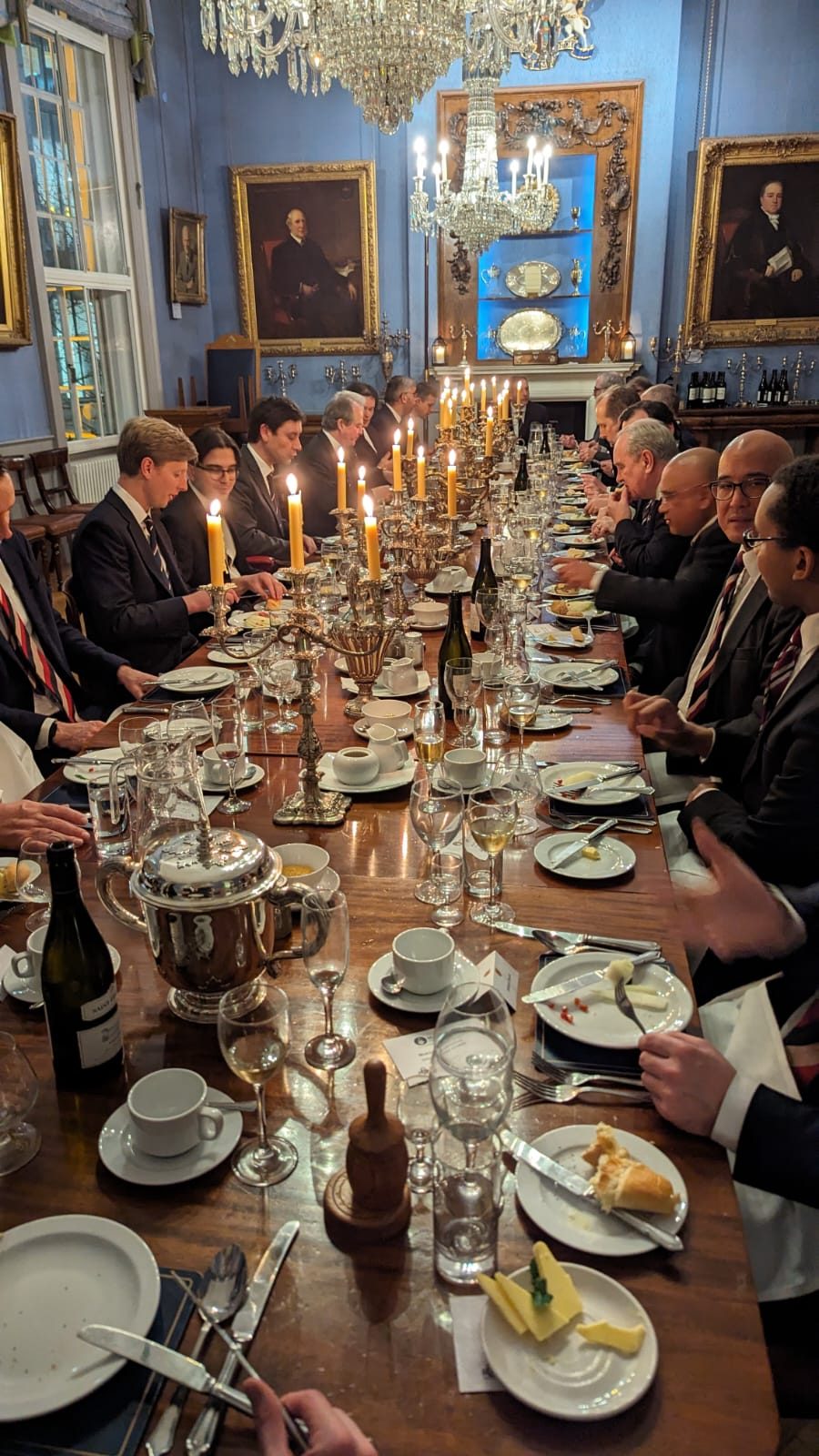 The long table laid for dinner beneath the portraits and chandeliers